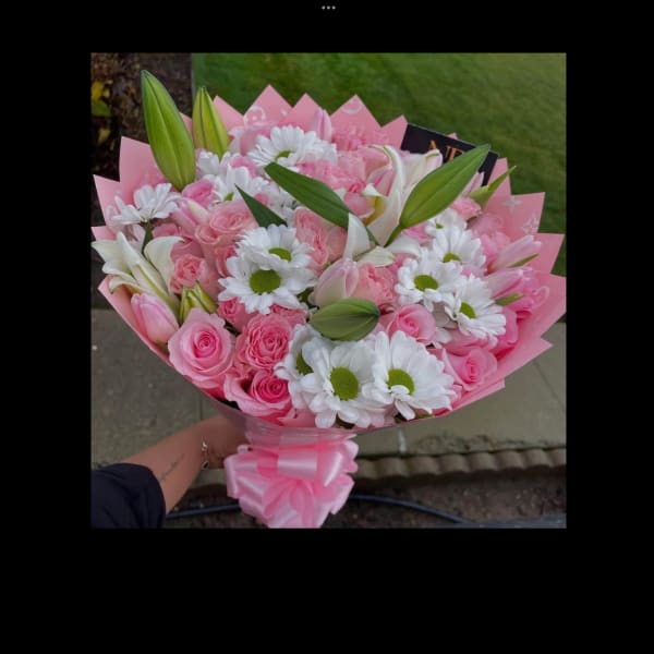 Pink bouquet of roses, daisies, and lilies wrapped in pink paper