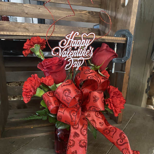 Red roses and carnations in a vase with a Happy Valentine's Day sign