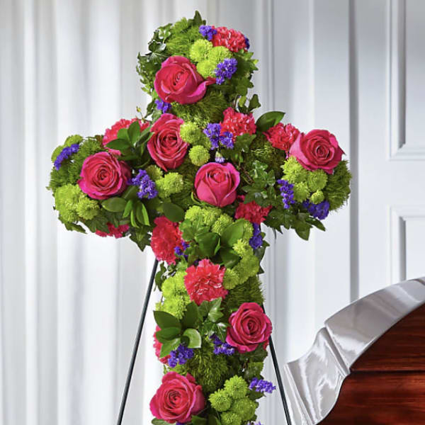 Cross-shaped floral tribute with pink roses and green pompons