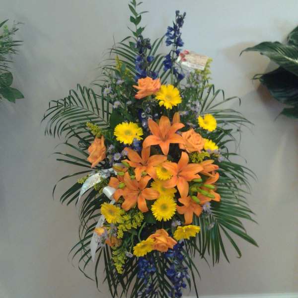 Tall standing floral spray with orange lilies and yellow daisies