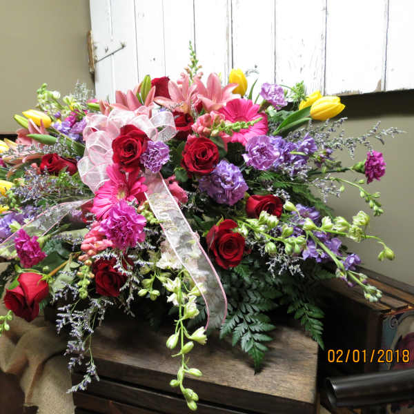 Large mixed bouquet of roses, lilies, and purple flowers with a ribbon