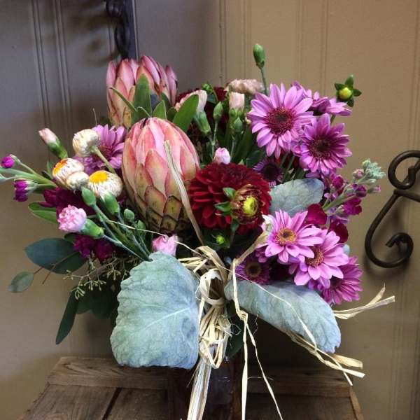 Mixed bouquet with pink protea and purple daisies in a vase