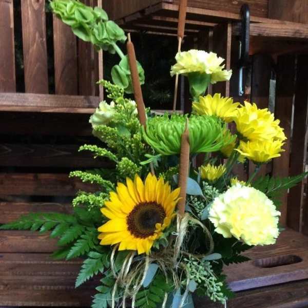 Sunflower and yellow carnation arrangement in a green vase