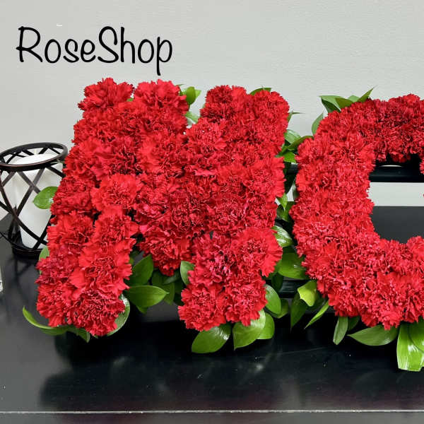 Red carnation letters spelling MOM with green leaves