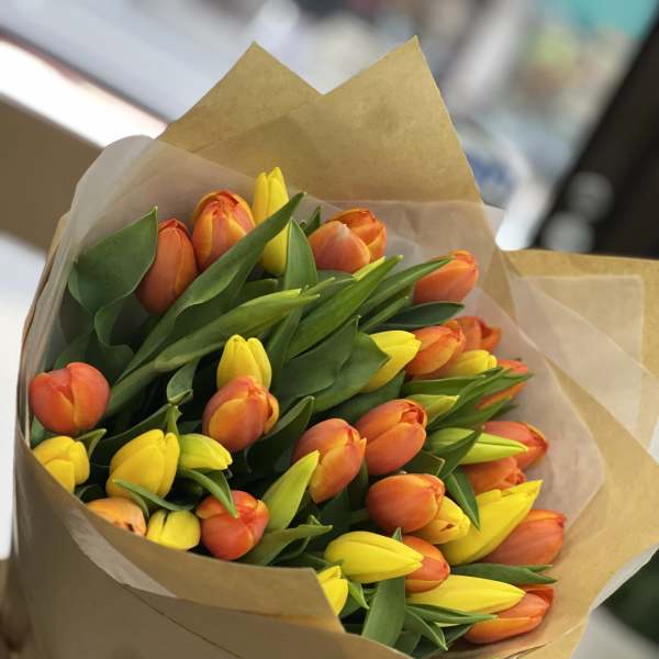 Bouquet of orange and yellow tulips wrapped in brown paper