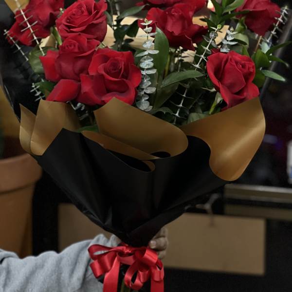Bouquet of red roses wrapped in black and gold paper with a red ribbon