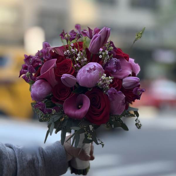 Handheld bouquet of purple and red flowers with a wrapped stem