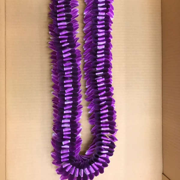 Purple lei made of layered petals on a cardboard background
