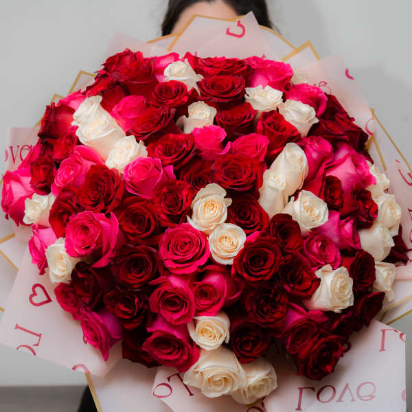 Large bouquet of red, pink, and white roses wrapped in printed paper