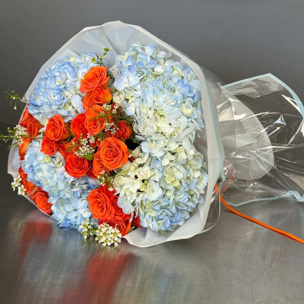 Bouquet of blue hydrangeas and orange roses wrapped in white paper