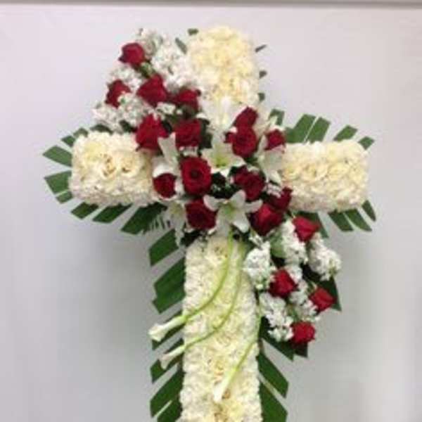 Cross-shaped floral tribute with red and white flowers on an easel