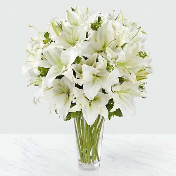 White lilies arranged in a clear glass vase