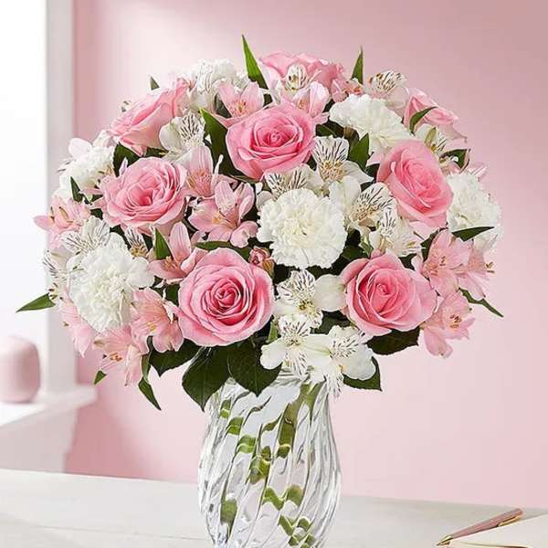 Pink roses and white flowers arranged in a clear glass vase