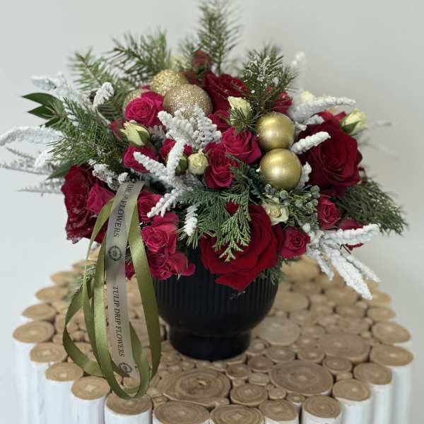 Red roses and pink spray roses in a black vase with gold ornaments