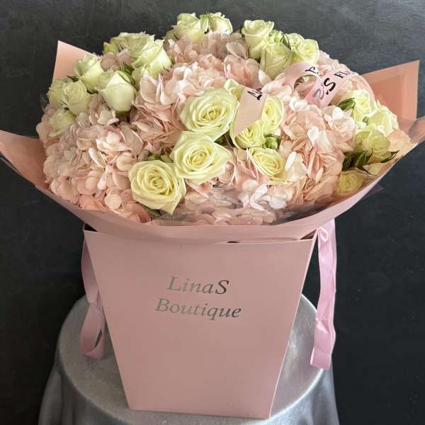 Pink bouquet with cream roses and pale hydrangeas in a pink box