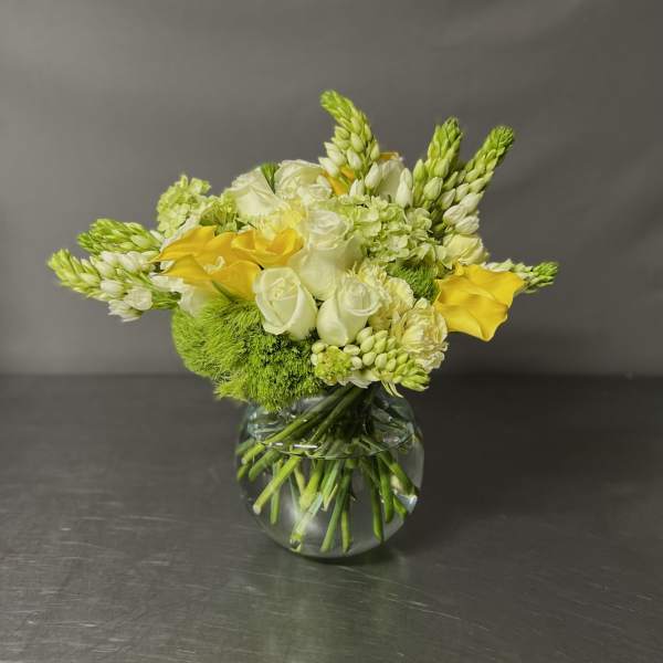 Yellow and white flowers arranged in a clear glass vase