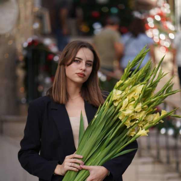 Woman holding a large bouquet of yellow gladiolus flowers