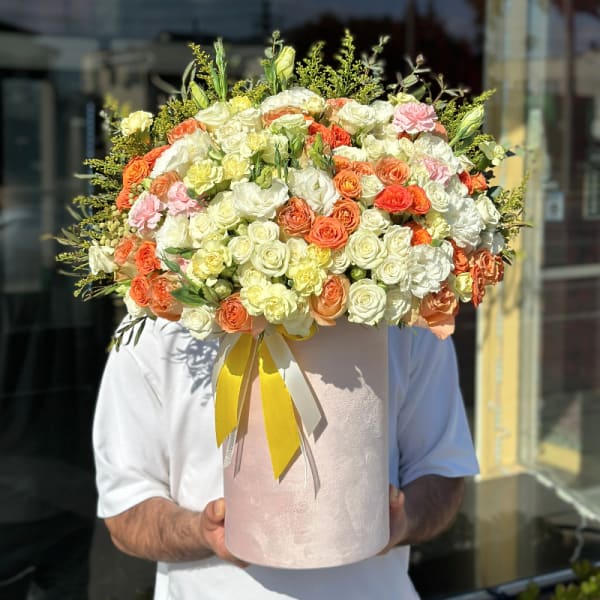Large bouquet of cream, peach, and pink roses in a pink hatbox
