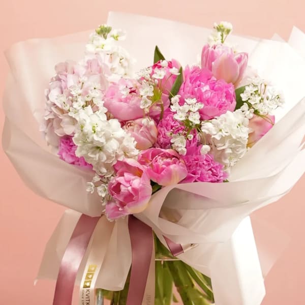 Pink tulip and peony bouquet with white blossoms wrapped in sheer paper