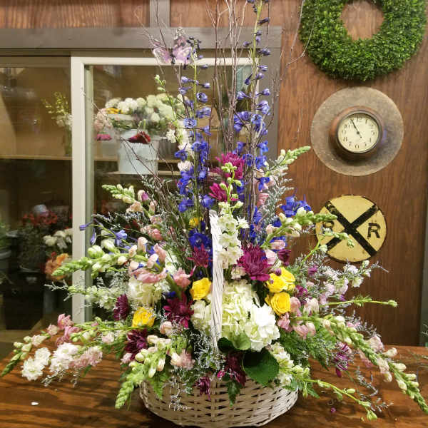 Large mixed flower arrangement in a wicker basket with tall branches
