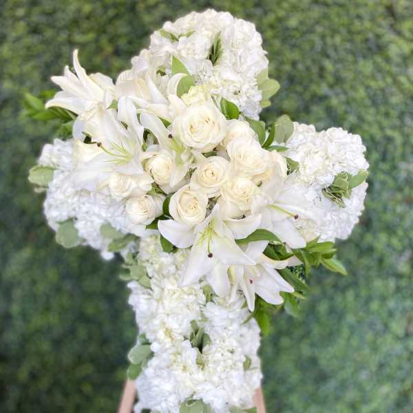 White floral wedding arrangement on an easel with lilies and roses
