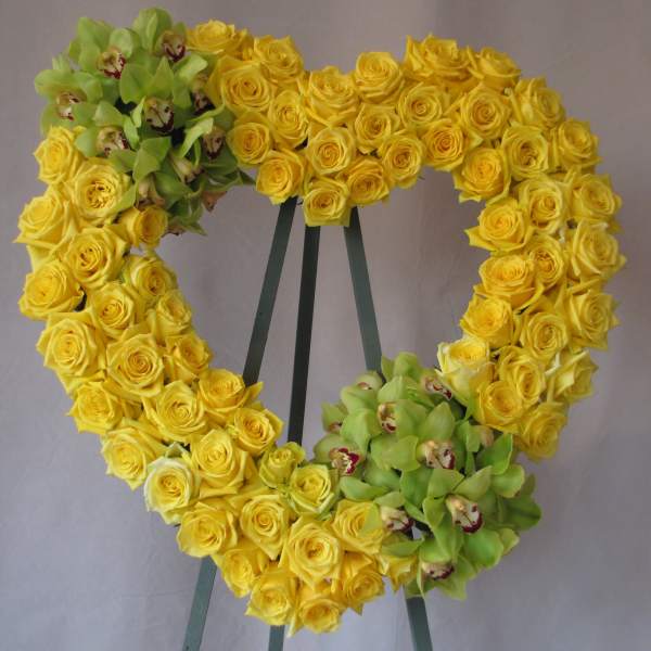 Heart-shaped wreath of yellow roses with green orchids on an easel
