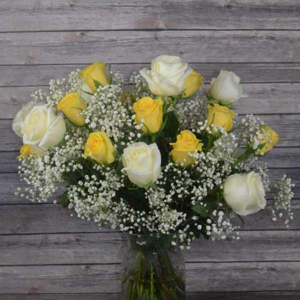 Yellow and white roses in a glass vase with baby's breath