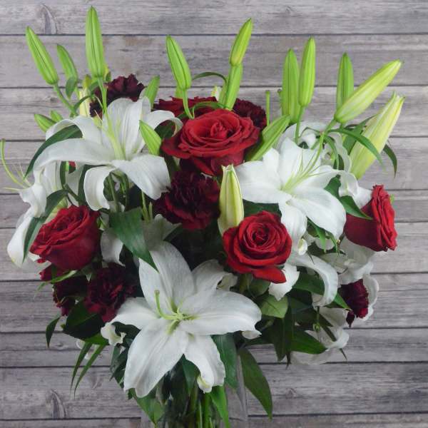 Bouquet of red roses and white lilies in a clear glass vase