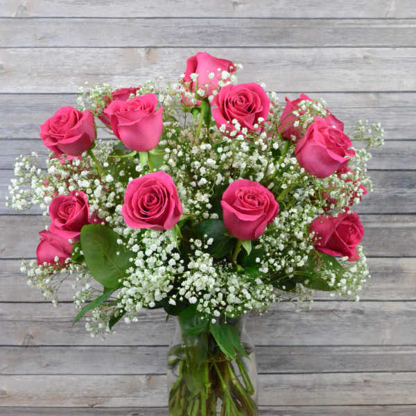 Pink roses arranged with white baby's breath in a clear glass vase