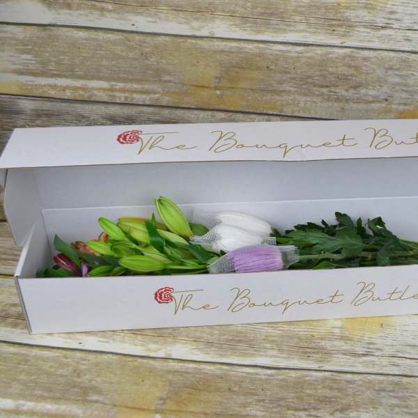 Boxed bouquet of lilies in bud form with tissue wrapping