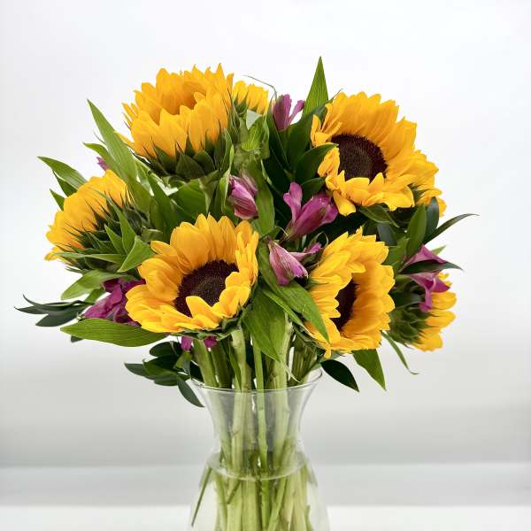 Sunflowers and purple alstroemeria in a clear glass vase