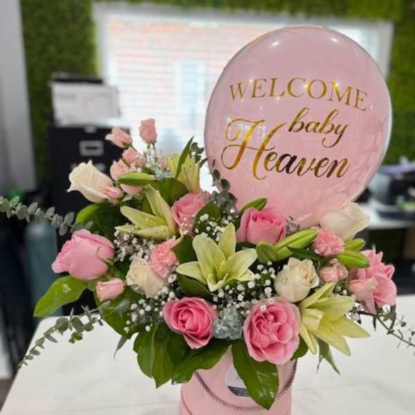 Pink and white floral arrangement with a baby shower balloon