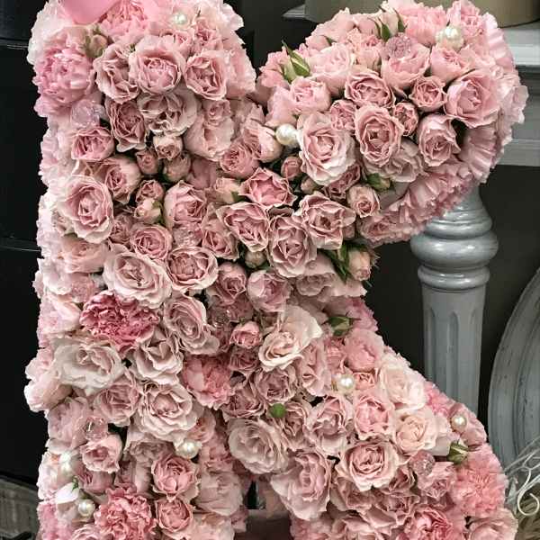 Pink rose teddy bear with pearl accents on a wooden base