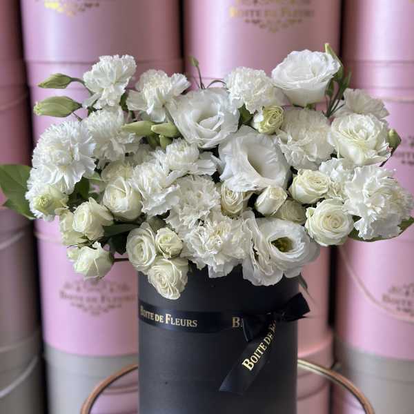 White roses and carnations arranged in a black hat box