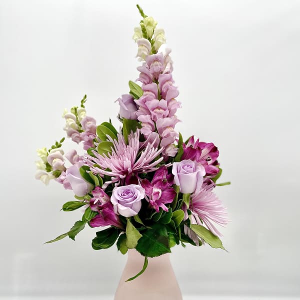 Pink and lavender flowers arranged in a pale pink vase