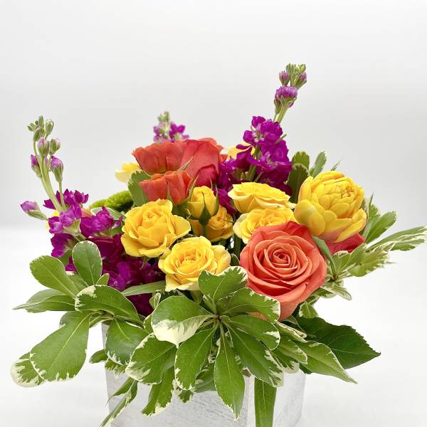Colorful bouquet of yellow, coral, and purple flowers in a white box