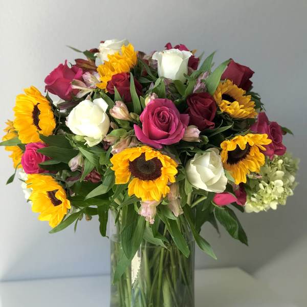 Bouquet of pink and white roses with sunflowers in a glass vase