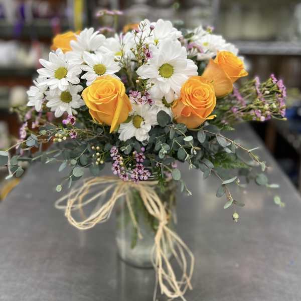 Bouquet of orange roses and white daisies in a glass vase