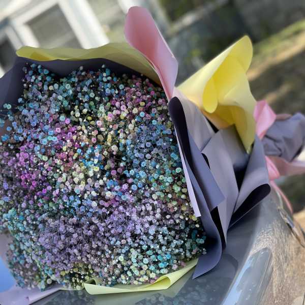 Bouquet of tiny multicolored flowers wrapped in pastel paper