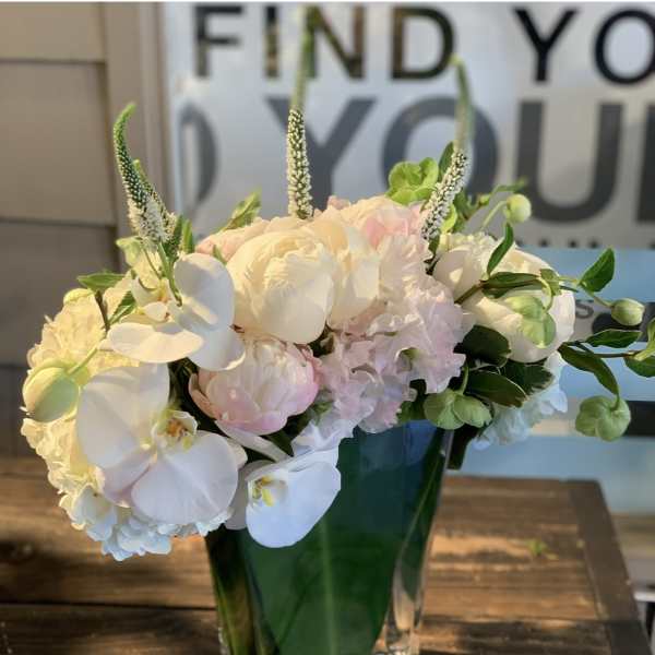 White and pale pink floral arrangement in a clear glass vase