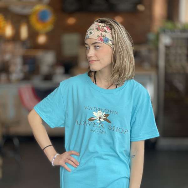Woman wearing a turquoise flower shop T-shirt and floral headband