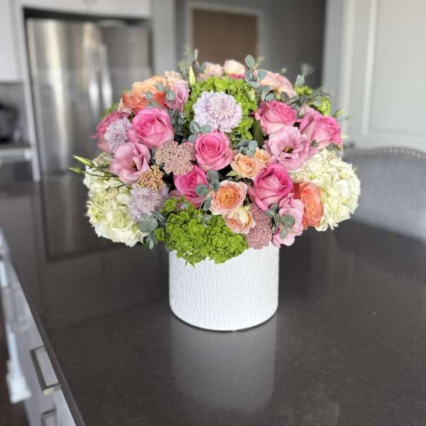 Pink and peach flower arrangement in a white vase