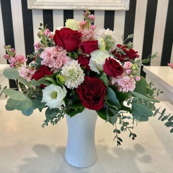Red and white roses with pink flowers in a white vase