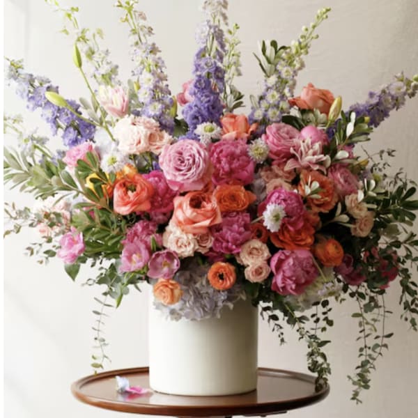 Large mixed bouquet in a white vase with pink, orange, and purple flowers