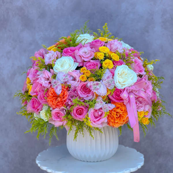 Large bouquet of pink, white, yellow, and orange roses in a white vase