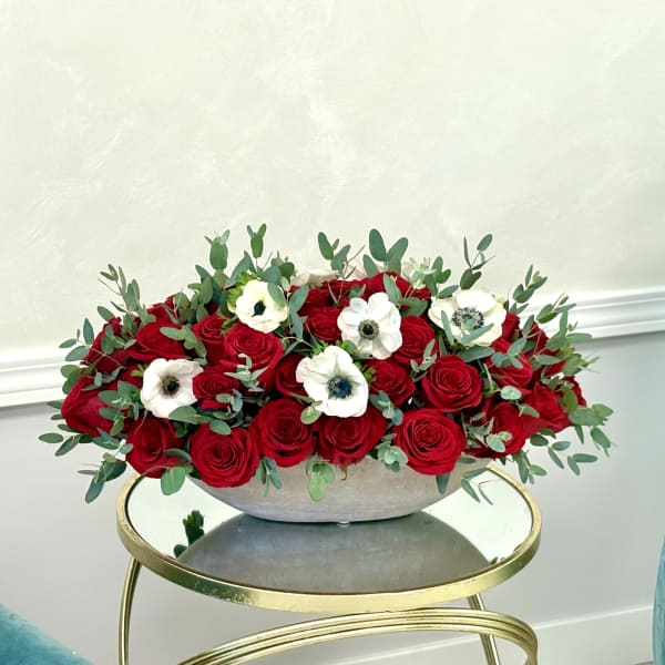 Red roses and white anemones in a low gray bowl