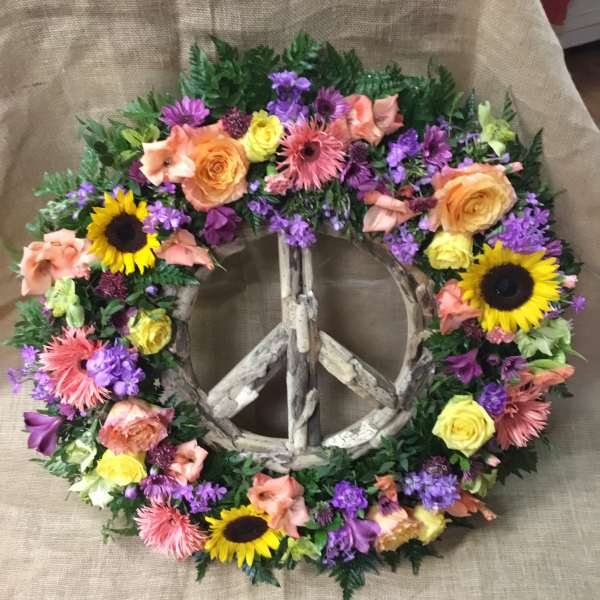 Floral peace sign wreath with sunflowers, roses, and purple blooms