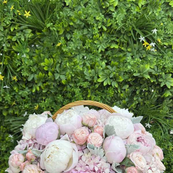 Pastel pink and white flowers arranged in a wicker basket