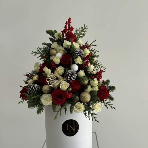 Red and white roses arranged in a white hat box with pinecones and gold ornaments