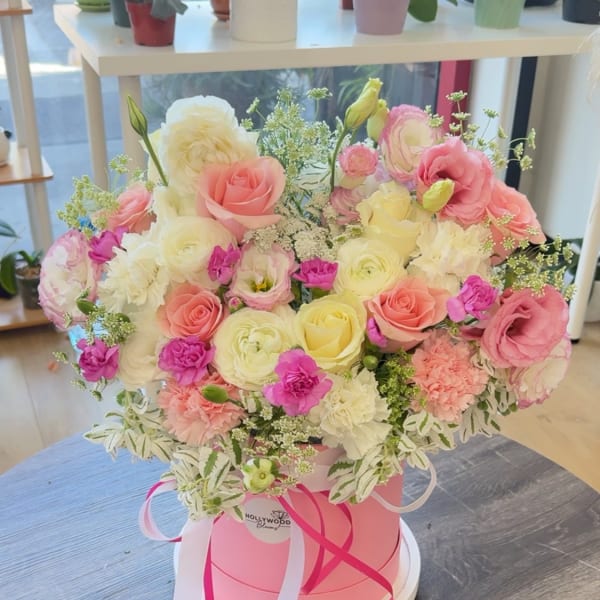 Pink and cream rose bouquet in a round pink box with ribbons